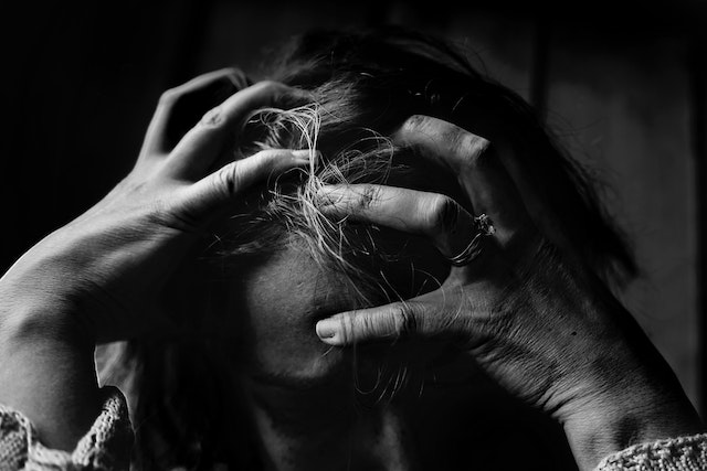 black-and-white-image-of-woman-who-is-stressed-clenching-her-hands-on-her-head
