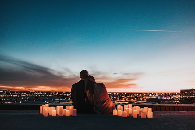 couple surrounding by candles looking out at dark night sky