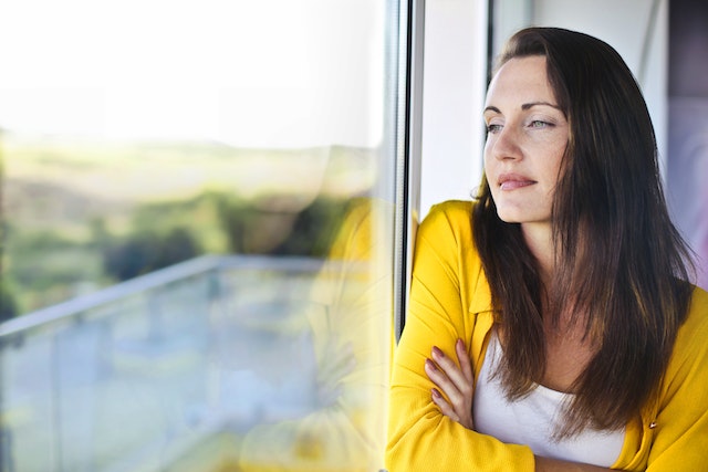 woman standing by window looking out