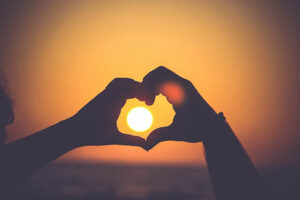 silhouette of two hands forming a heart