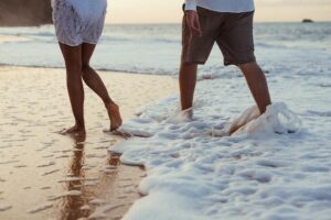 photo of a couple walking on the beach in the water