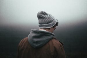 photo of a man wearing a jacket standing in nature looking at fog