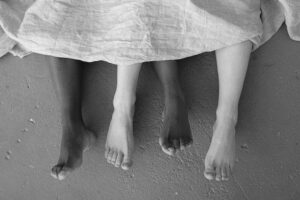 couple in bed only feet showing out of blanket