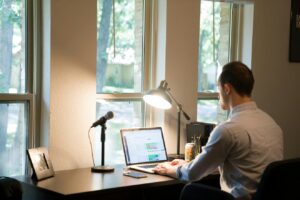 man-in-white-dress-shirt-sitting-on-chair-using-laptop-computer