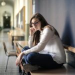 woman-in-white-long-sleeve-shirt-and-blue-denim-jeans-sitting-on-table